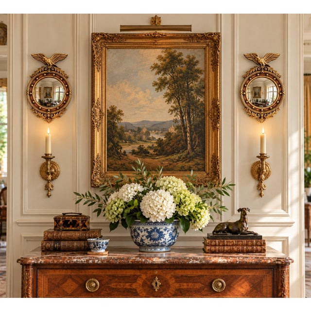 A pair of Federal-style convex mirrors crowned with carved eagles, their wings outstretched above a laurel motif—an...