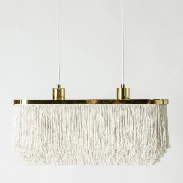 “Fringe” ceiling lamp by Hans-Agne Jakobsson, made with a rectangular brass and acrylic glass frame. Drapes of textile...