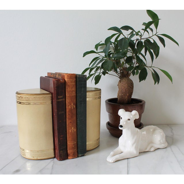 Pair of vintage cream and gold colored leather wrapped bookends. No makers mark. Some age wear to leather. Pictured.