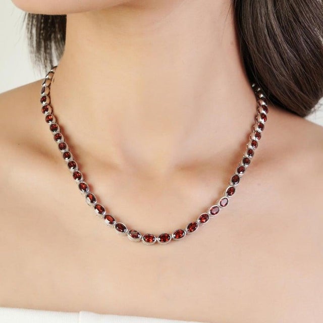 This refined tennis necklace is crafted in 925 sterling silver and set with 57 natural garnet gemstones, each beautifully...