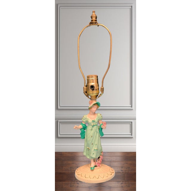 This exquisite metal lamp depicts a young woman with pink flowers in her left hand. She walks as if in a trance, head...