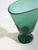 This green blown glass pedestal vase by Vetro Verde di Empoli, produced in Italy circa the 1950s, demonstrates a fluid...