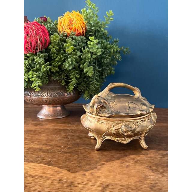 Antique Art Nouveau style jewelry casket featuring ornate sculpted roses and flowing floral motifs in warm brass tone...