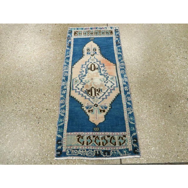 This mid-20th-century Turkish Anatolian rug, measuring 1' 6" × 3' 5", presents a striking interplay of form and color,...