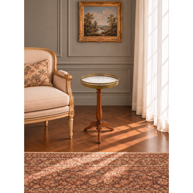An elegant French guéridon side table featuring a circular Carrara marble top encircled by a pierced brass gallery....