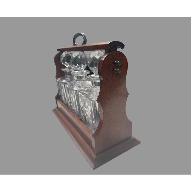 Impressive vintage three-bottle locking Tantalus liquor decanter set featuring three matching heavy cut-glass decanters...