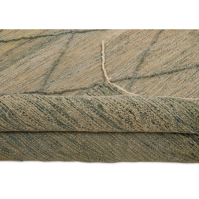 Elegant handwoven wool rug featuring a soft diamond lattice pattern. Against a backdrop of Neutral Taupe, muted Olive...