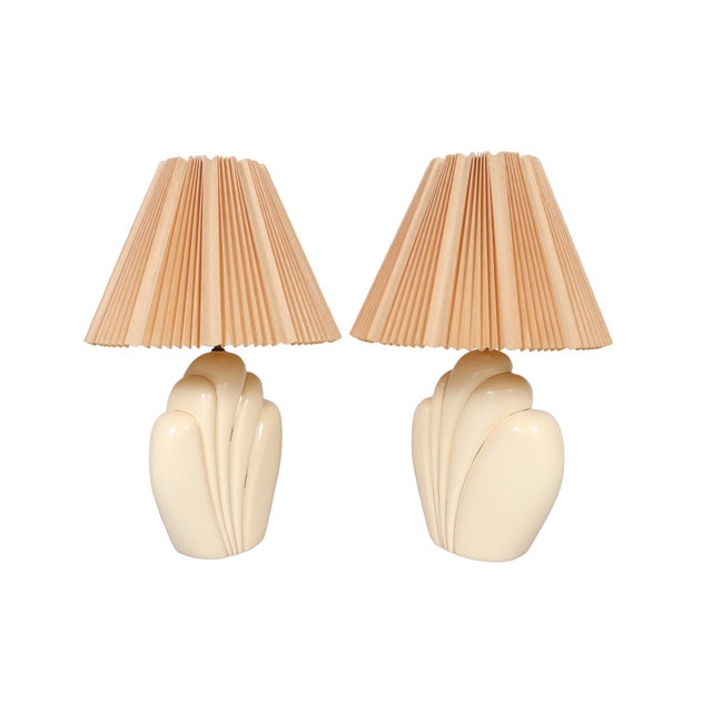 A pair of sculptural ceramic table lamps in cream. Vases are shaped like feather plumes trimmed with gilt lines. Lamps are...