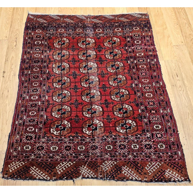 A refined early 20th century Turkmen Tekke area rug showcasing a detailed allover geometric gul medallion design of...