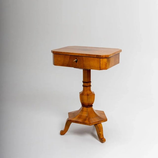 Elegant Biedermeier sewing table in walnut with an octagonal tabletop and a single drawer. The vase-shaped, hexagonal...