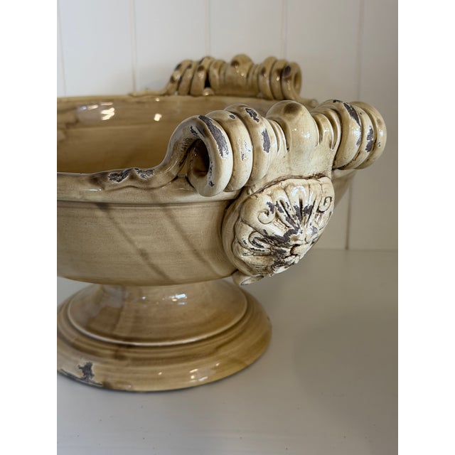 A beautifully handcrafted ceramic pedestal compote featuring an elegant sculptural silhouette with richly detailed scroll...