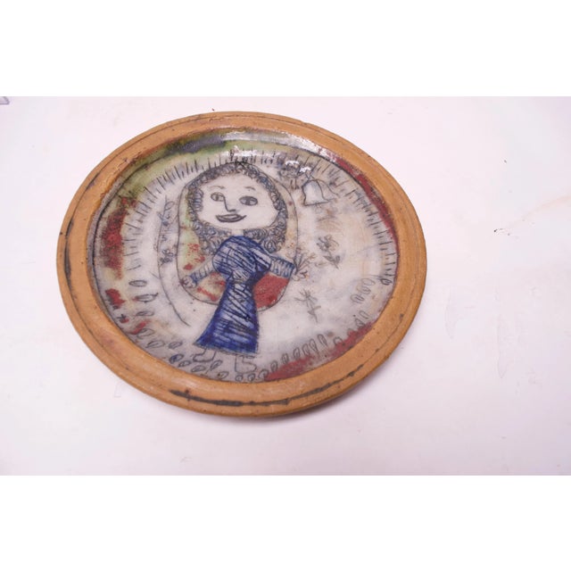 Charming outsider art charger / decorative plate depicting a jovial young girl. Pleasant color palette and figure with...