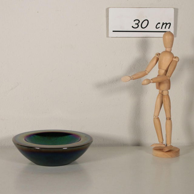 This glass catch-all features colored glares in yellow, green, blue, purple and fuchsia. It was made in Murano, Italy, in...