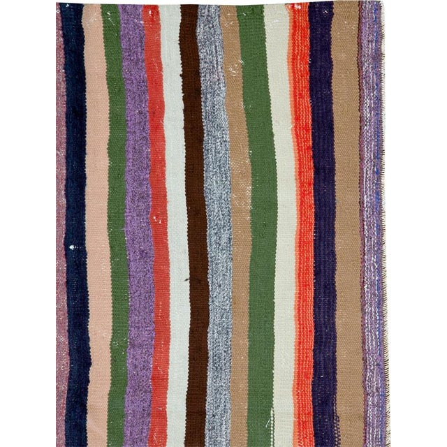 This mid-20th century Persian flatweave kilim rug offers a refined and rhythmic interpretation of tribal striping. Woven...