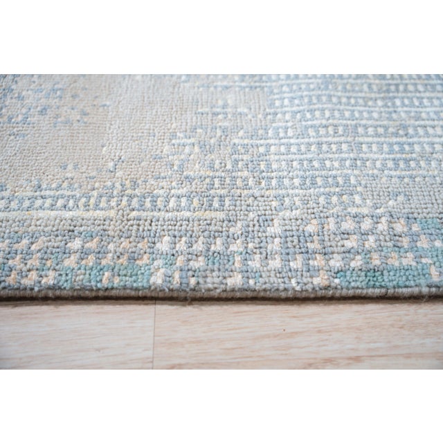A hand-knotted wool rug, made in India and measuring 9' x 12'. Loose, abstract drawing rather than a formal repeating...