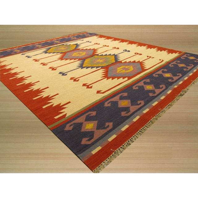 A handwoven wool flatweave, made in India and measuring 5' x 8'. Geometric drawing - repeating motifs held inside strong...