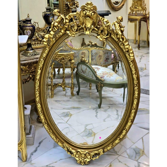 Magnificent French-style wall mirror featuring an elaborately hand-carved frame adorned with intricate floral motifs and...