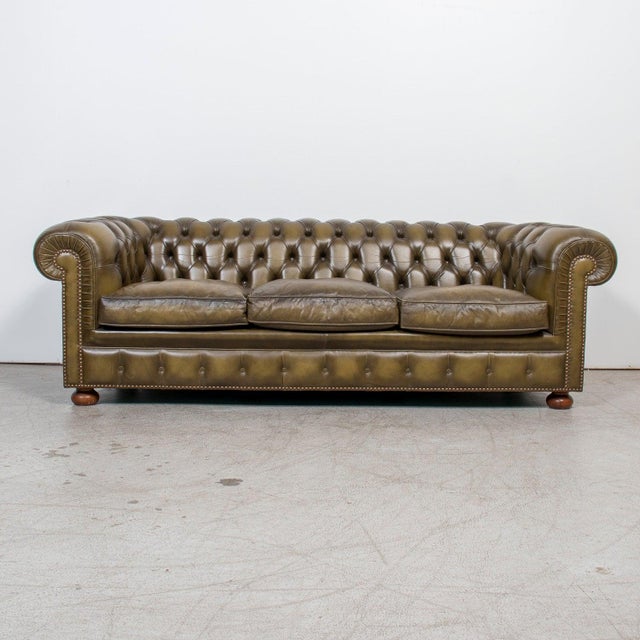 A striking vintage English Chesterfield sofa in rich olive green leather, crafted in the Victorian style during the...