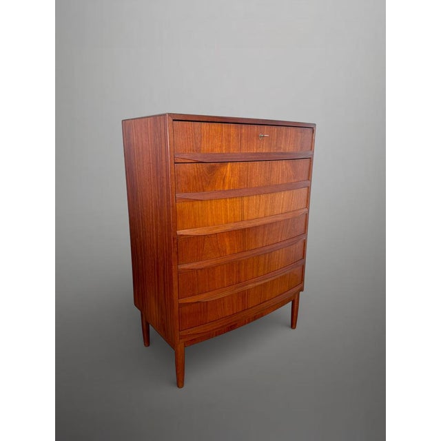 This Scandinavian mid-century chest of drawers features elegant curved drawer fronts, tapered legs and a top drawer with...
