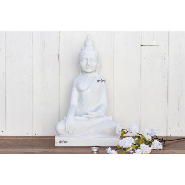 Truly of piece of art, this beautiful hand-carved statue of a sitting Buddha in pure white marble has finely carved facial...