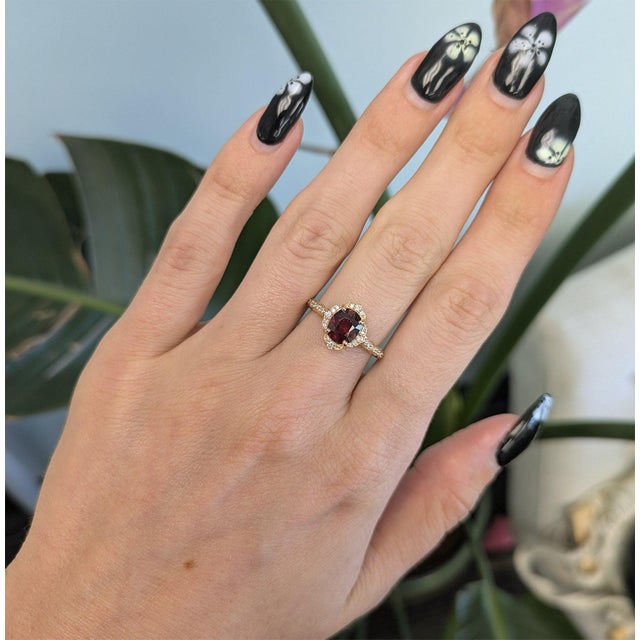 A natural red spinel glows with vivid, fiery red at the centre of this solid 14K yellow gold ring, surrounded by thirty-...