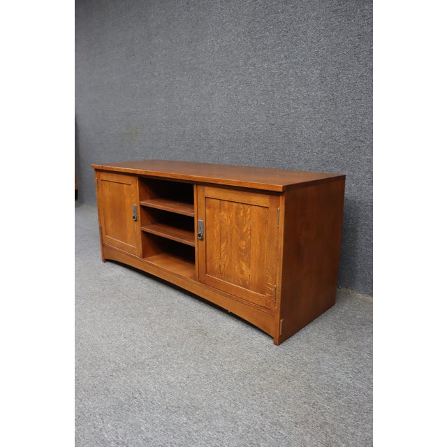 Stickley oak media console in a Mission style design with clean lines and paneled doors. Features two side cabinets with...