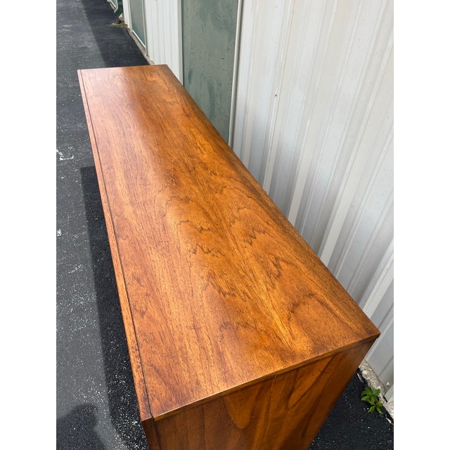 A long triple dresser made by Dixie Furniture in the 1960’s. Brutalist in style, this dresser features nine total drawers,...