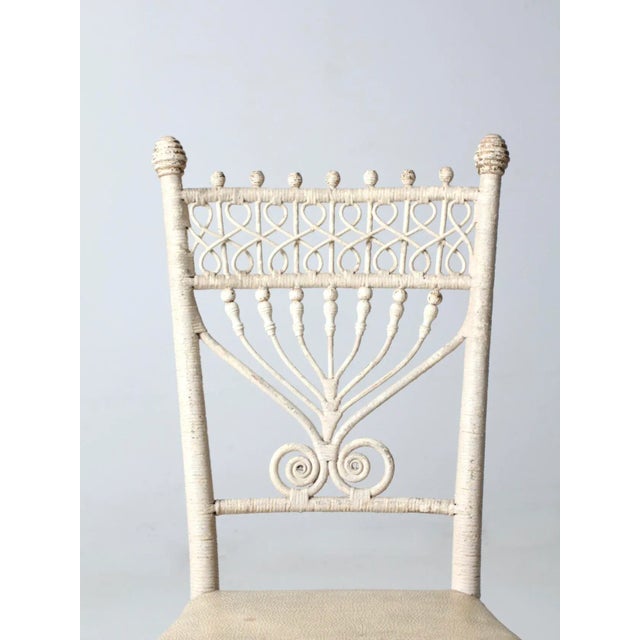 This is an antique wicker chair circa late 19th century. The ornate Victorian wicker chair features a coil an bead back...