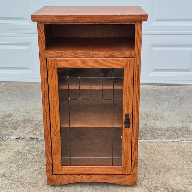 This is a mission or arts & crafts style oak veneer cabinet with a leaded glass door by Aspen Furniture. It is originally...