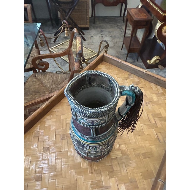 Enchanting Moroccan pitcher crafted in terra-cotta, decorated in distinctive colors, glazed and adorned with jewelry like...