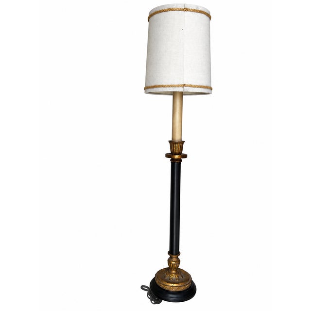 An elegant candlestick-form table lamp featuring a slender black column, gold-tone ornamental accents, and an ivory...