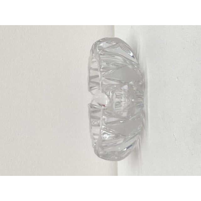 Circular ashtray in molded and cut crystal, with thick walls, featuring a geometric design of facets, diamond points, and...