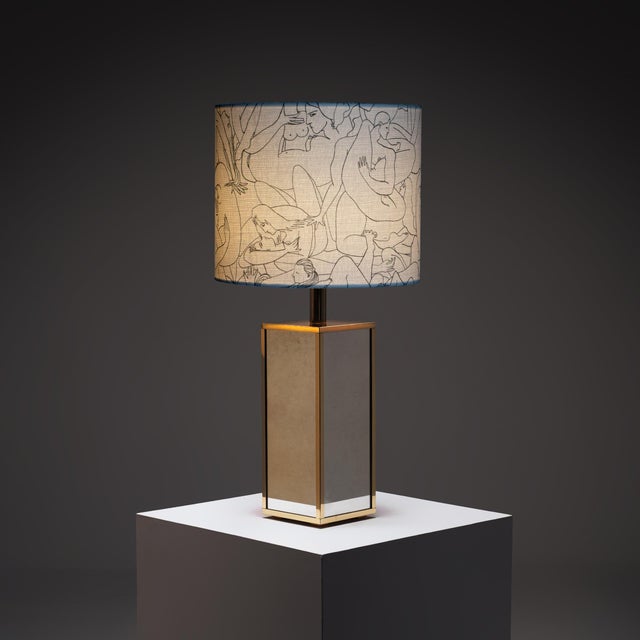 A sculptural presence, this mirrored table lamp balances geometry, reflection, and softness in a composition that feels...