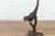 A bronze lost wax cast statue of a parrot leaning on a tree branch with dark patina. Created with the traditional...