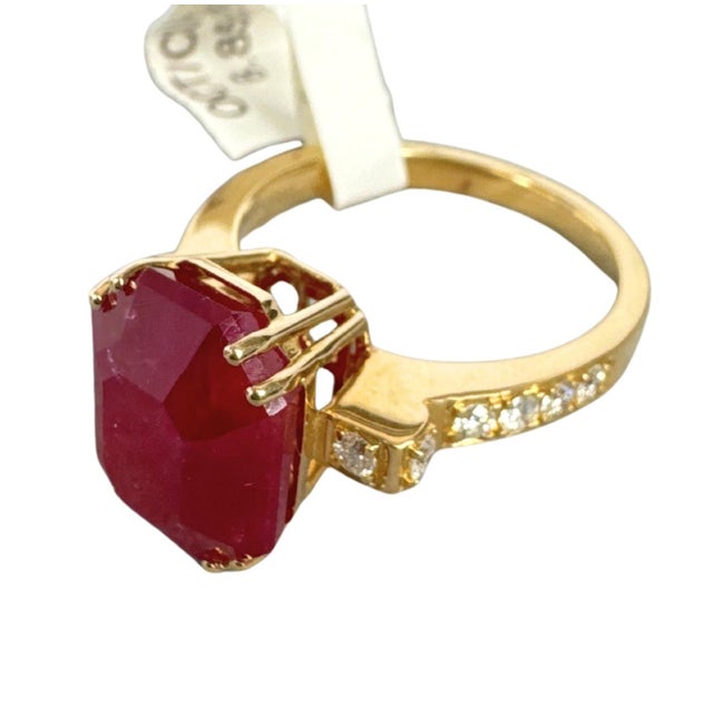 Centering an 8.34 carat natural ruby, this striking ring features an emerald-cut stone with a rich semi-transparent...