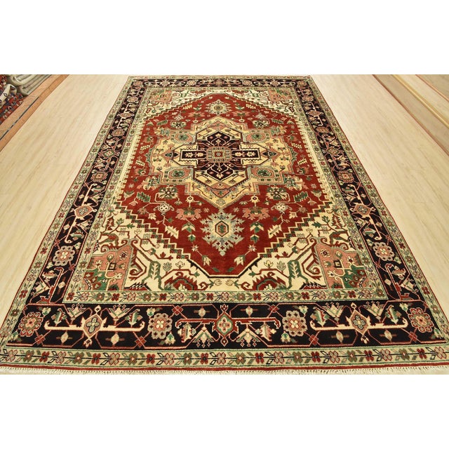 A traditional tribal Heriz rug hand-knotted with an all-wool pile on a cotton foundation. This oriental rug features a...
