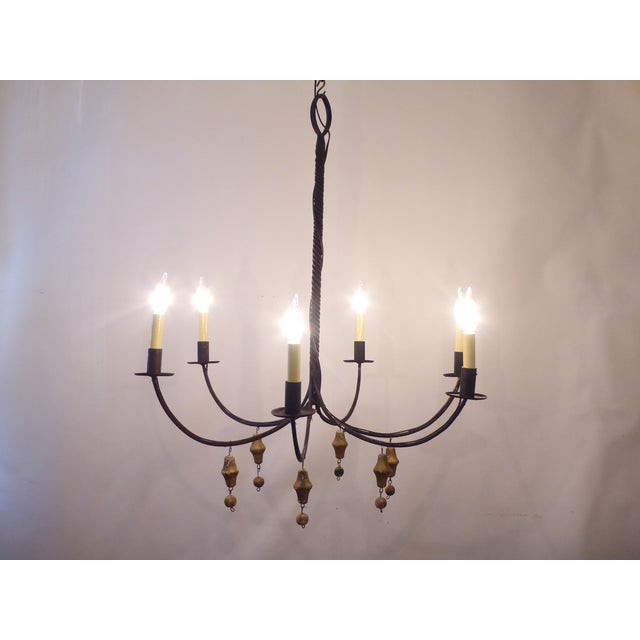 This rustic wrought iron chandelier has wooden pendants and uses up to 60 Watt candelabra bulbs.