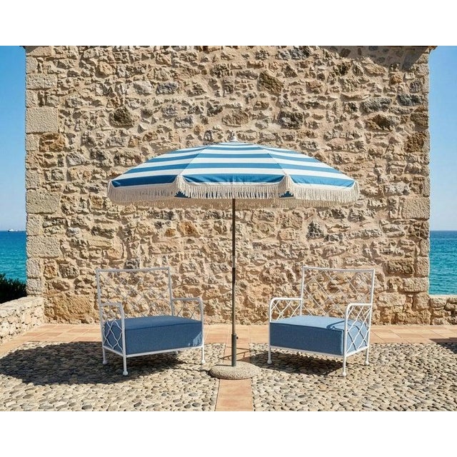 An elegant pair of French 20th century wrought iron lounge chairs after Jean Royere. The chairs feature crisp white...