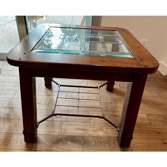 Solid wood frame with exposed pegs/fasteners Inset glass top (not just resting on top) Hand-forged style metal grid under...