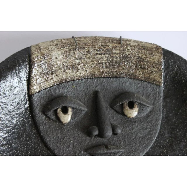 A ceramic plate with a nun in reliëf, where the nun takes the shape of the plate. Atelier Dour was founded in 1947, right...