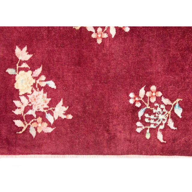 A stunning early 20th century petite Chinese Art Deco rug with a cranberry field with two chrysanthemum clusters in...