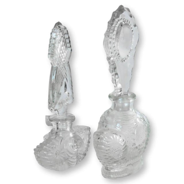 a Pair of midcentury pressed glass perfume bottles. Unsigned. Dimensions: large, 3.5"W x 2"D x 7"H; small, 3.5"W x 2"D x...