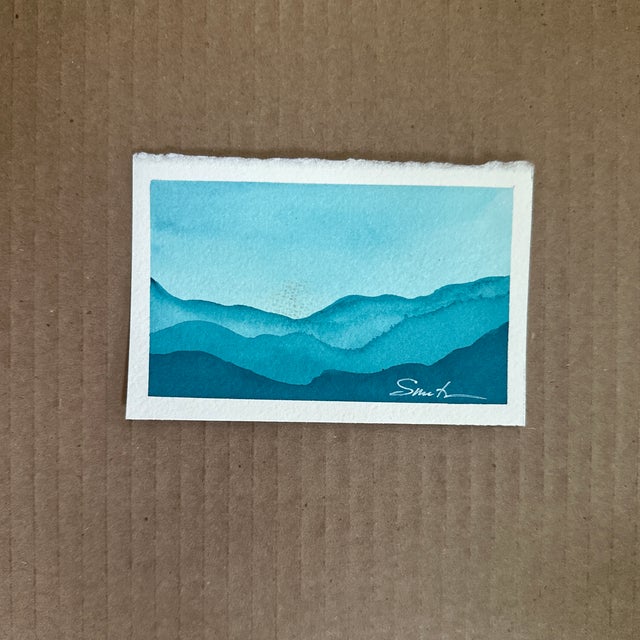 A serene watercolor miniature landscape in cool turquoise tones, capturing the peaceful rhythm of distant mountains fading...