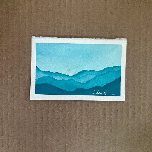 A serene watercolor miniature landscape in cool turquoise tones, capturing the peaceful rhythm of distant mountains fading...