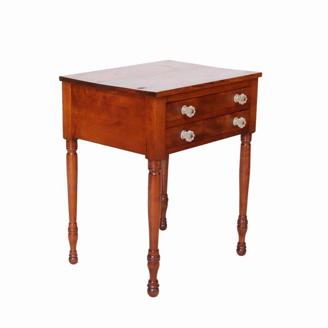 An antique Sheraton two-drawer stand, crafted from rich cherry wood, dating to approximately 1840. This piece features a...