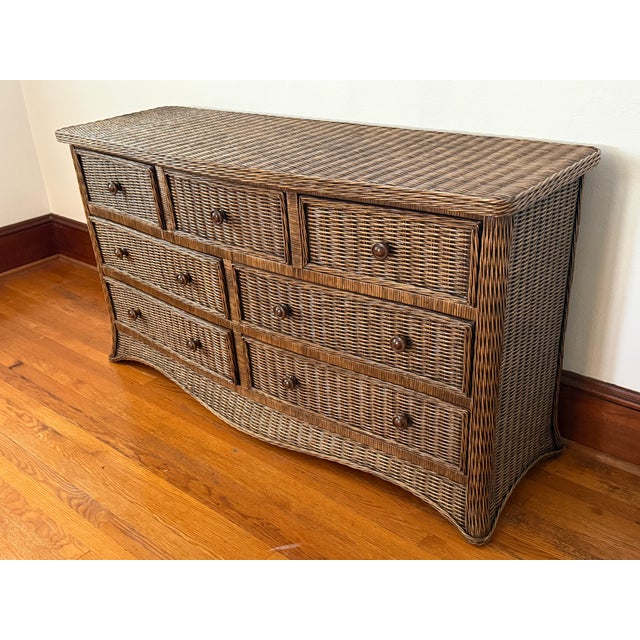 Skirted bow front dresser fully wrapped in woven rattan. It has seven drawers; three smaller drawers run across the top,...