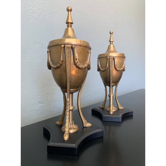Pair of Neoclassical Style Antique Brass Mantle Urns with Lids. Solid Brass with Swags and Finials. Black Wooden Bases. In...
