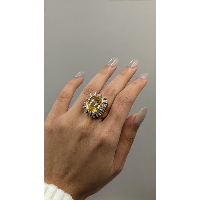 This exquisite ring features a stunning Yellow Sapphire at its center, weighing 13.38 carats, which radiates a warm and...