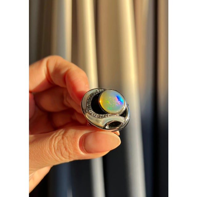 This stunning statement ring showcases a cabochon opal set beneath onyx, accented with Mother of Pearl carvings, pavé...