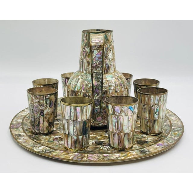 Elegant mid-century Mexican serving set featuring a round tray, water pitcher, and eight matching cups, crafted in solid...